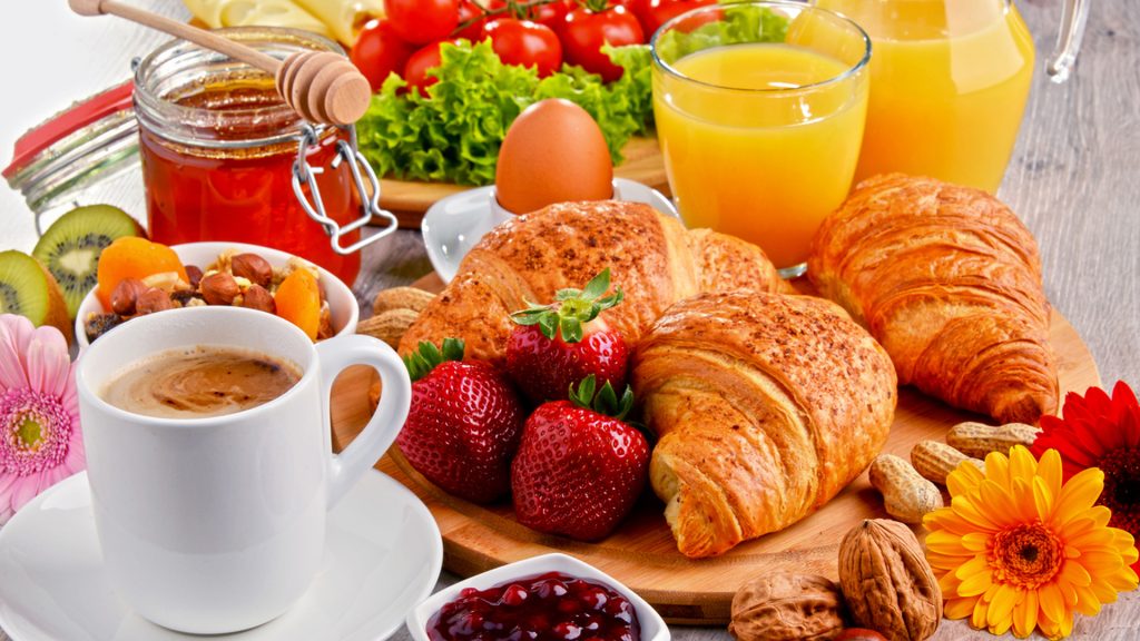 breakfast consisting of croissants, coffee, fruits, orange juice